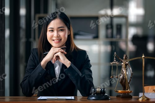Preview: Portrait of beautiful female lawyer sitting at desk, smiling at camera.
