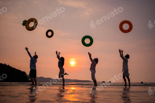 Preview: Family jumping and playing on the beach at sunset, silhouettes reflected on wet sand