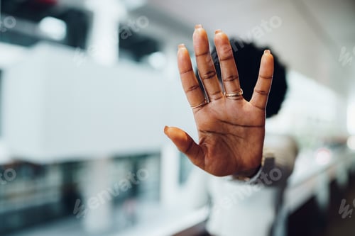 Preview: Portrait of a serious young african woman showing stop gesture with her palm in urban background