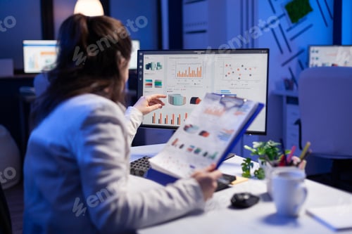 Preview: Freelancer woman comparing graphics from clipboard with grafics from computer