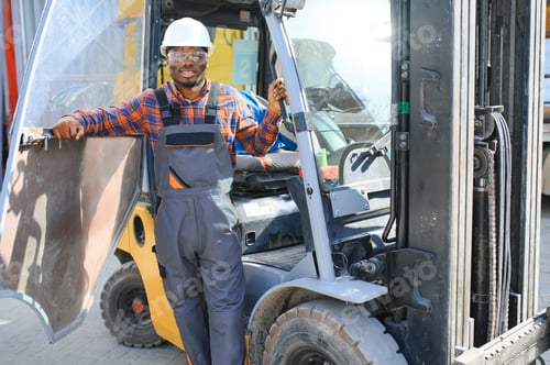 Preview: Portrait of a happy African American male worker driving forklift at workplace