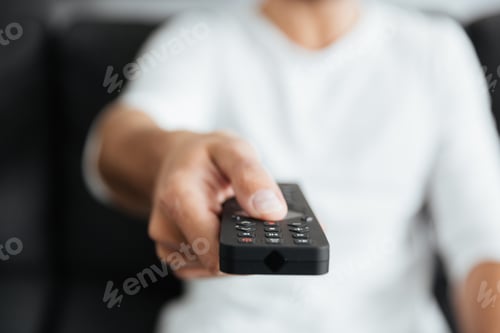 Preview: Cropped image of young man holding remote control.