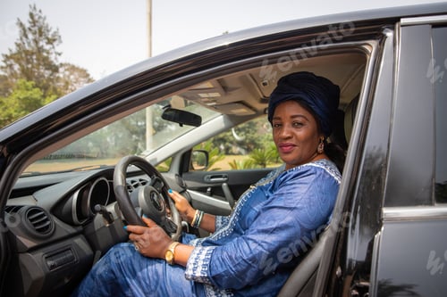 Preview: African woman sitting inside the car with her hands grabbing the steering wheel