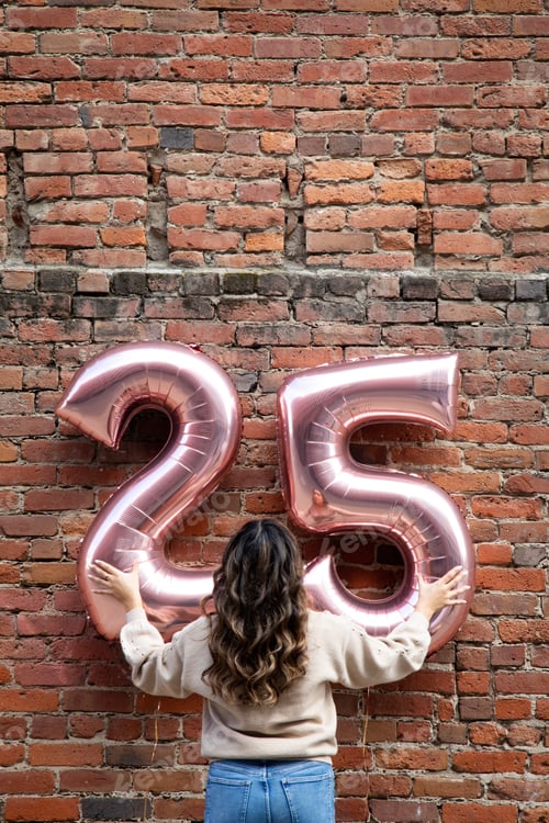 Preview: Young woman holding number twenty five balloons. Birthday wishes. Brick wall. Beautiful brown hair