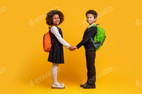 Preview: School kids with backpacks holding hands on yellow background