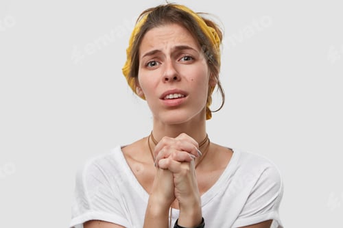 Preview: Please, do me favour. Pretty young lady with miserble look, keeps palms in pray, dressed in casual c