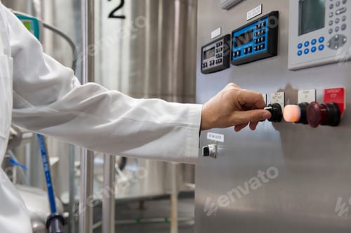 Preview: A technician in a white coat turns on the controls to processing tanks in a large bottling plant.