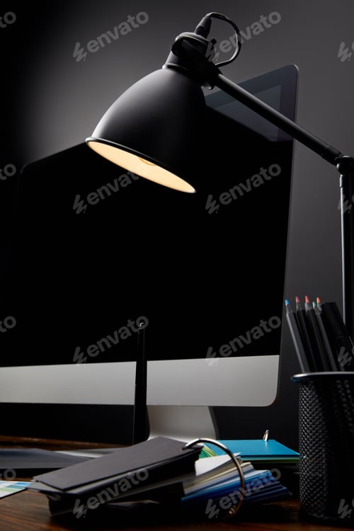 Preview: close up view of designer workplace with lamp and blank computer screen on wooden tabletop