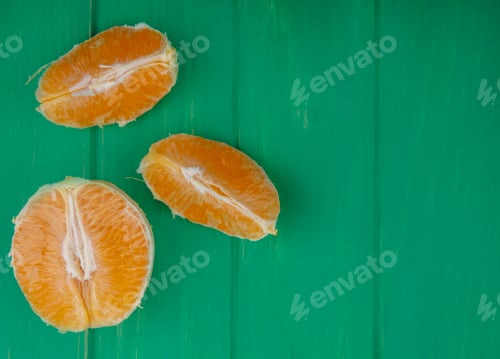 Preview: top view copy space peeled orange slices on green background