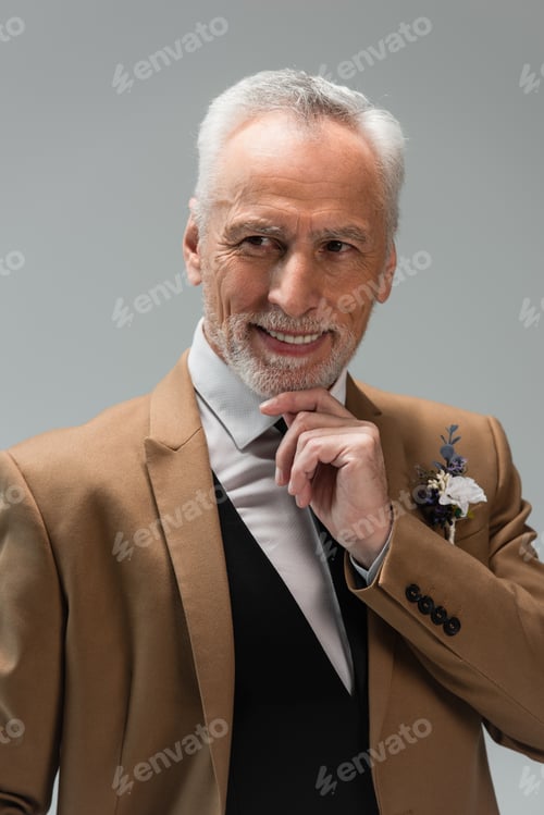 Preview: cheerful middle aged groom in suit with floral boutonniere isolated on grey