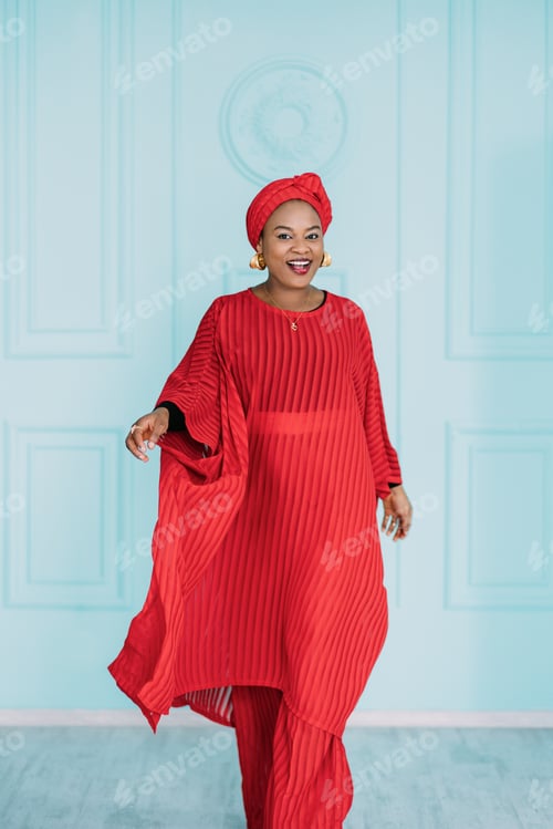 Preview: Beautiful positive african american woman wearing red ethnic clothes and headscarf, walking on