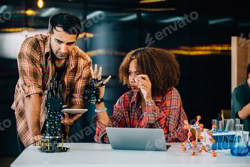 Preview: Teacher assists student building a robotic arm in classroom for design and technology. Encouraging