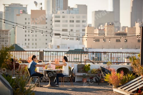 Preview: Couple Making Toast To Celebrate Birthday On Rooftop Terrace With City Skyline In Background
