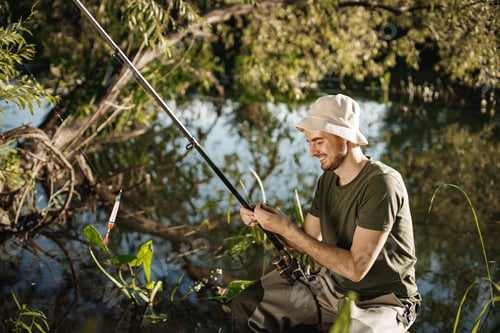 Preview: Young fisherman with fishing rod near the lake at summer