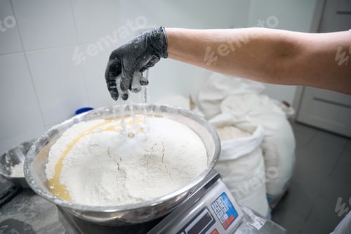 Preview: Cook pours flour into a metal bowl