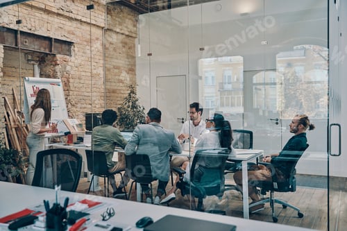Preview: Modern young woman conducting a business presentation while standing in the board room