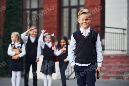 Preview: Group of kids in school uniform posing to the camera outdoors together near education building