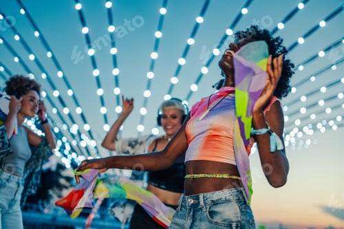 Preview: Young women dancing and enjoying music festival under decorative lights