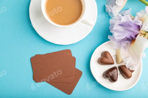 Preview: Brown business card with cup of cioffee, chocolate candies and iris flowers on blue pastel