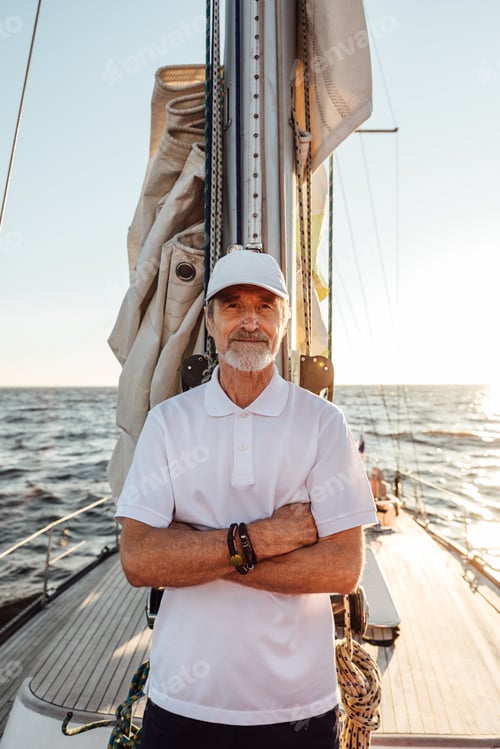 Preview: Portrait of a mature captain standing on his yacht at mast with crossed arms