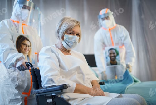 Preview: Doctors and covid-19 infected patient in wheelchair in hospital, coronavirus concept.