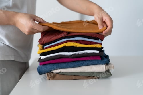 Preview: Housewife arranging clothes on white table, folding laundry and organizing closet