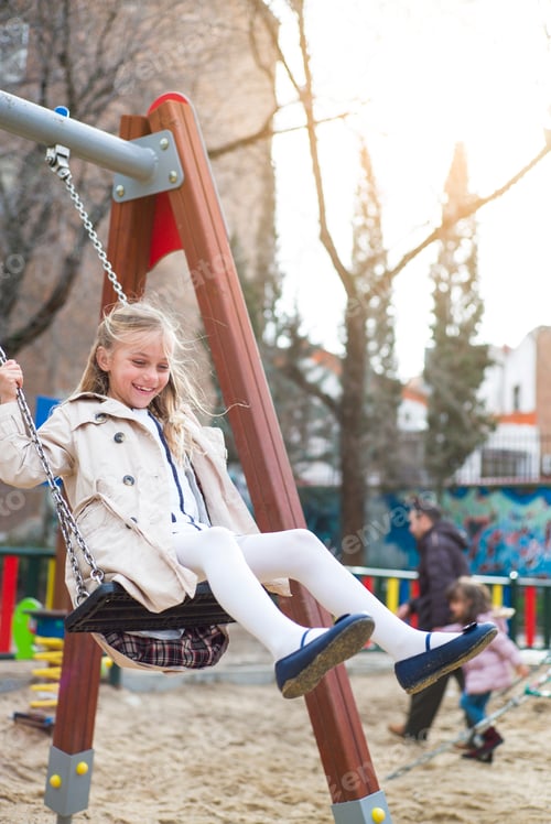 Preview: Smiling girl swinging in park