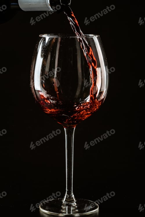 Preview: Red wine being poured in a wine glass on a dark background