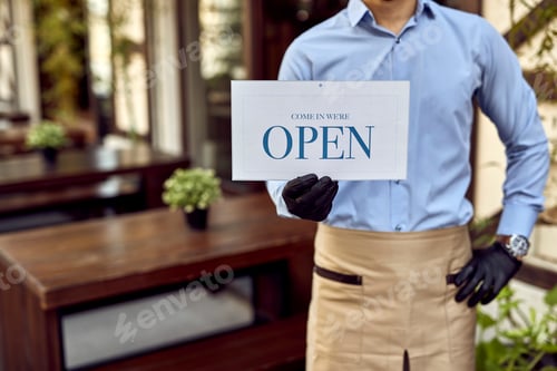 Preview: Unrecognizable cafe owner holding open sign and reopening after COVID-19 epidemic.