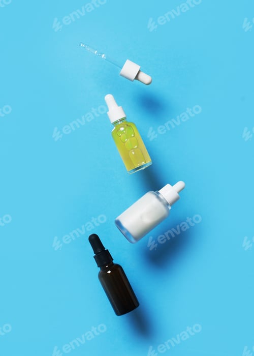 Preview: Beauty levitation concept with serum bottles on blue background,