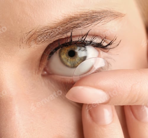 Preview: Young woman putting contact lens in her eye, closeup
