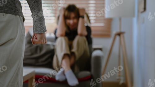 Preview: Man clenching fist in anger with crying woman in background. Domestic Family violence concept.