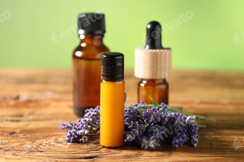 Preview: Bottles of lavender essential oil and flowers on wooden table, closeup