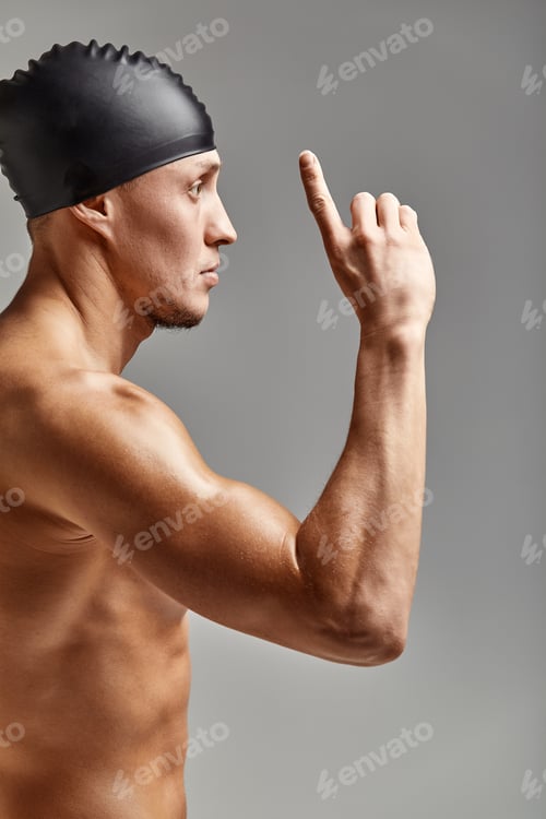 Preview: Young professional swimmer man indicates with fingers up showing a blank space.