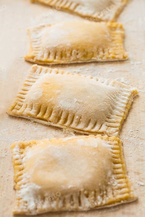Preview: Fresh ravioli with spinach and ricotta waiting to be cooked on wooden table. Selective focus