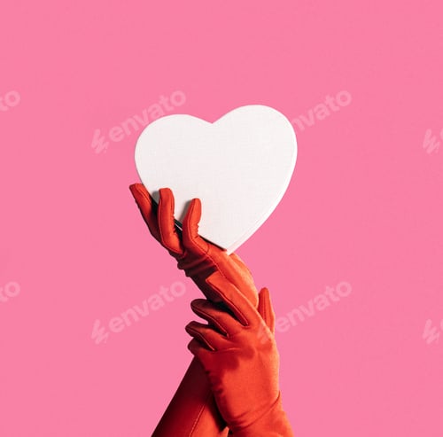 Preview: Female hands in red gloves hold pink heart on pink background