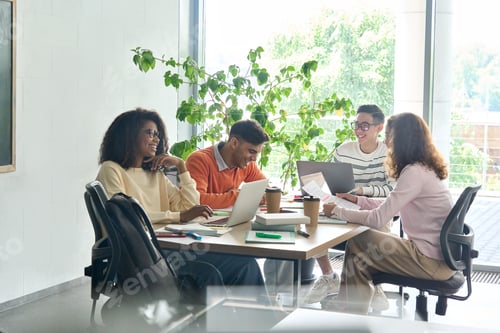 Preview: Four happy colleagues creative team working together in office using devices.
