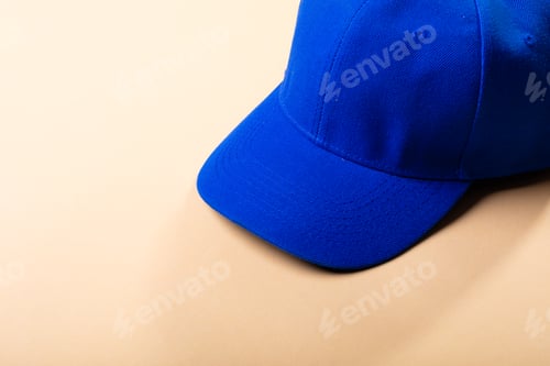 Preview: Composition of traditional peaked blue baseball cap on pale brown background