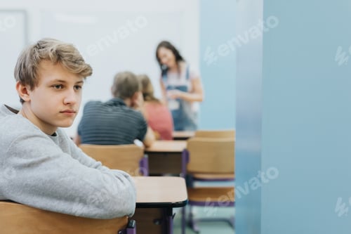 Preview: Thoughtful teenage boy sits on the side of a class during lesson at school