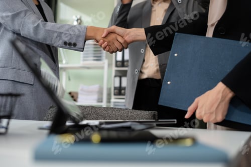 Preview: Happy businessman and businesswoman shaking hands at group board meeting.