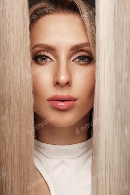 Vista previa: Hermosa chica rubia con un cabello perfecto y un maquillaje clásico con un mechón de pelo como extensión