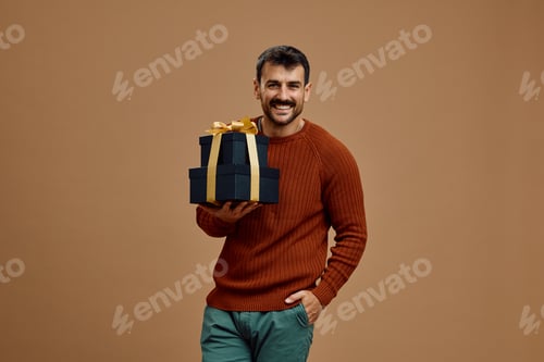 Preview: Studio shot of happy man with golden black gift boxes looking at camera.