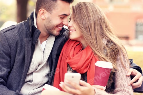 Preview: Romantic couple on a bench with smartphone in the park