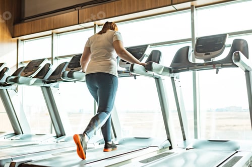 Preview: overweight girl working out on treadmill in gym against window