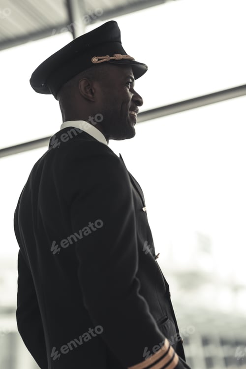 Preview: handsome young pilot looking away at airport