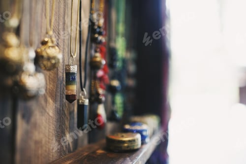 Preview: Closeup of crystal necklaces hanging on a wooden surface under the lights with a blurry background