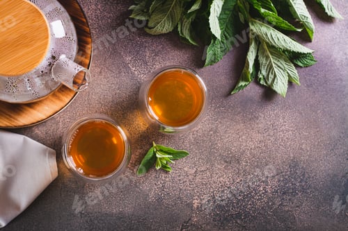 Preview: Fresh mint tea in cups and teapot and leaves on the table top view