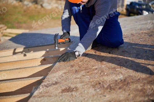 Preview: Carpenter hammering nail into OSB panel while building wooden frame house.