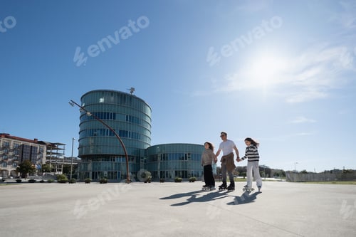 Preview: Father teaches daughters roller skating in city square on sunny day