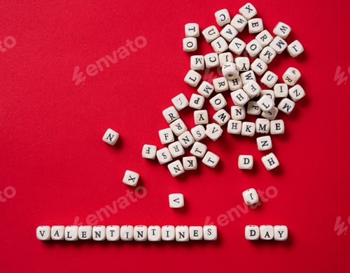 Preview: Flat lay Valentines day concept. On a red background is laid out of wooden game cubes